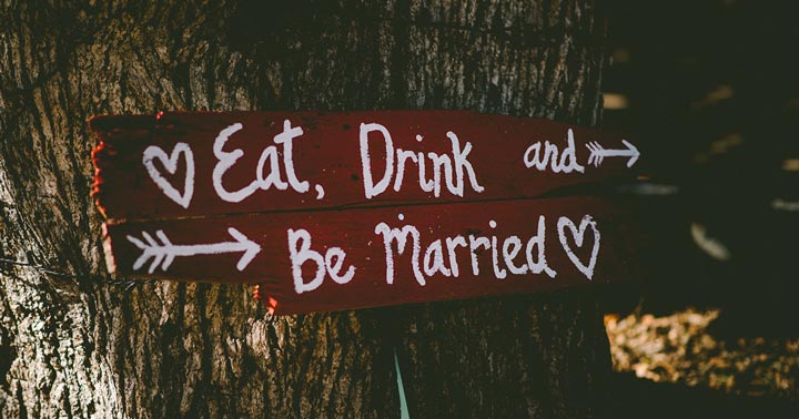 how to pay for a wedding without going broke; sign attached to a tree that reads eat, drink, and be married