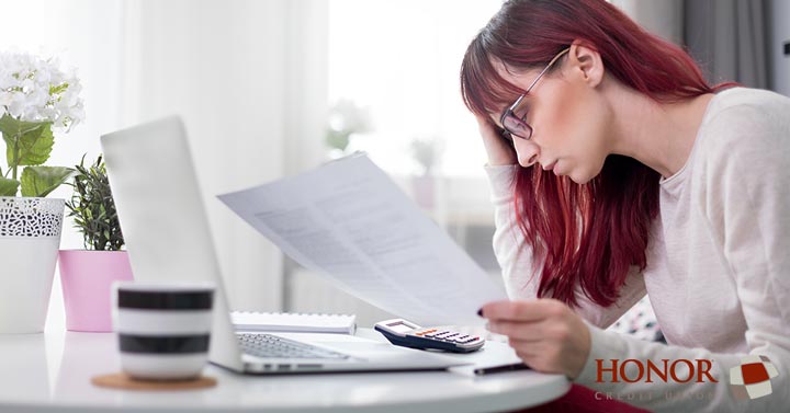 a few simple tips can help you maintain a balanced budget as a new college graduate; woman staring at papers at a desk