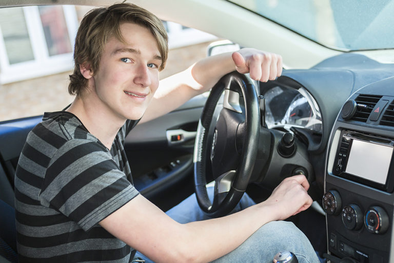 Teenager sitting in driver's seat of car