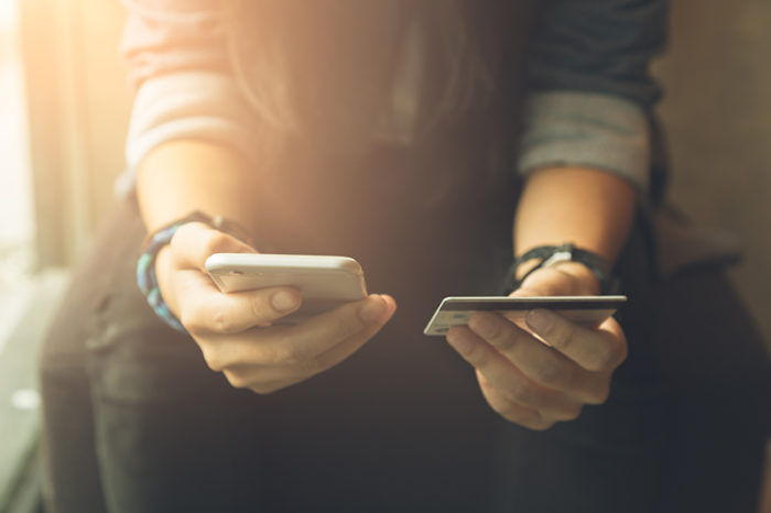 person holding a credit or debit card in one hand and a mobile phone in the other hand