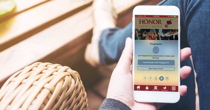 log in to the honor credit union app using a pin, fingerprint, facial recognition, voice, or a traditional password; image of a hand holding the honor app using the fingerprint login method