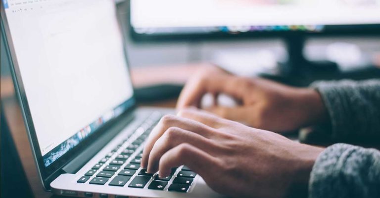 image of a person's hands typing on a laptop