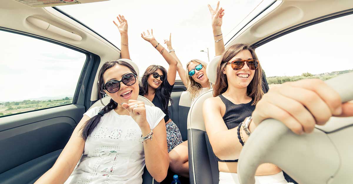photo of a group of girls having fun riding in a car on a sunny day