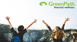 image of two hikers holding their hands up as they overlook a mountain peak