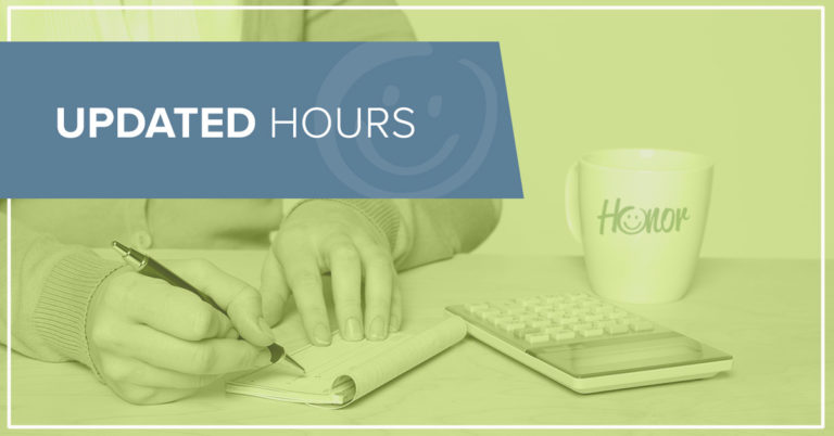 photo of a person writing a check at a table with a coffee mug and calculator also on the table