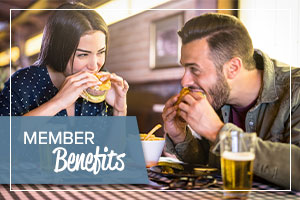 image of a man and woman eating food at a bar with text on the image promoting benefits for honor credit union members